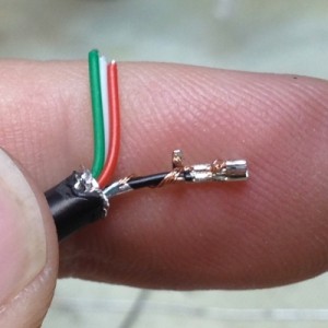 This is the partially-crimped connector. The bared wires of the black wire is crimped into the pin, and the tall strain-relief wings of the pin are still un-crimped. The bared wires of this particular cable were slightly longer than necessary. 